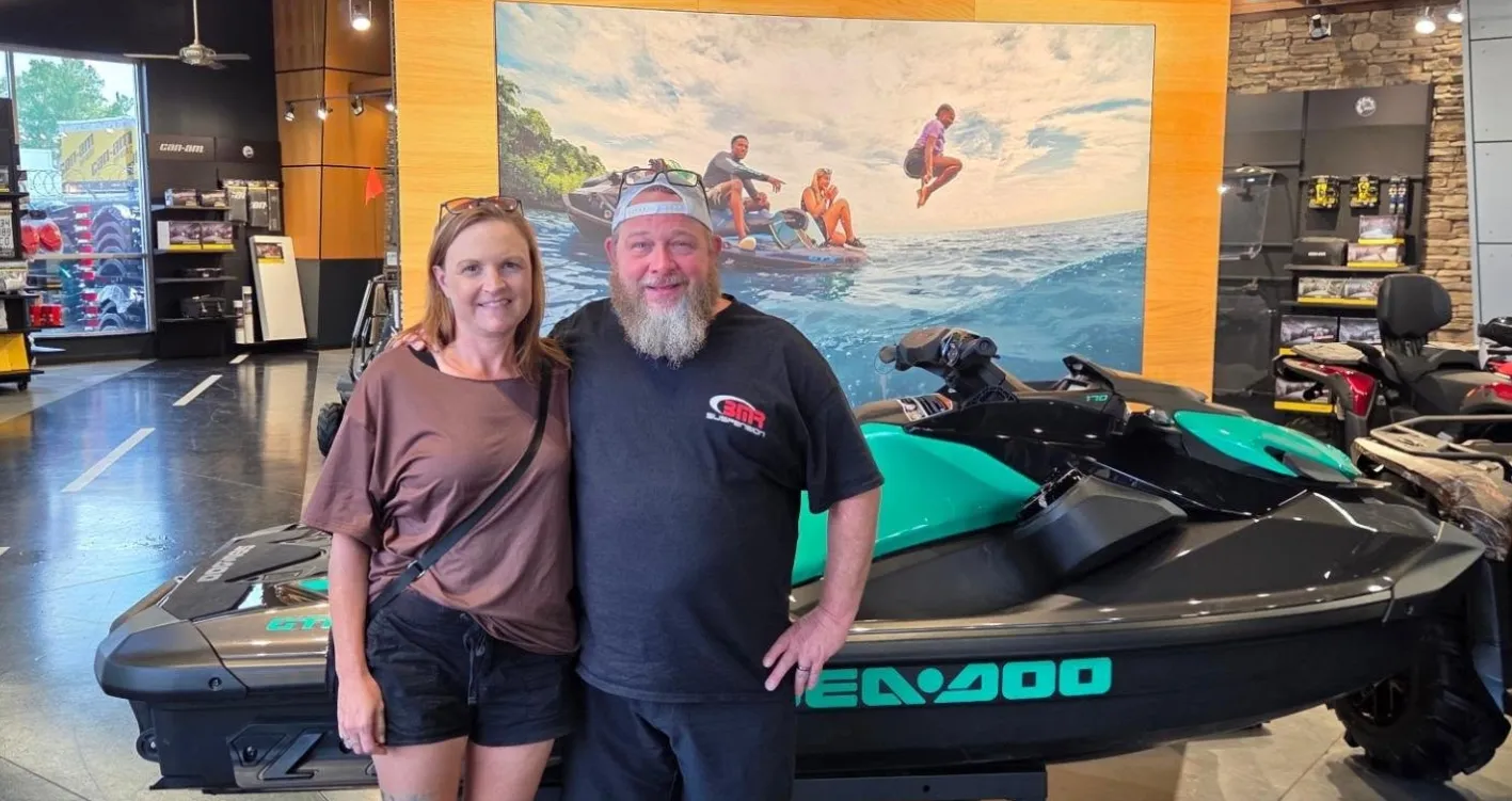 Customers beside a Sea-Doo watercraft in the showroom